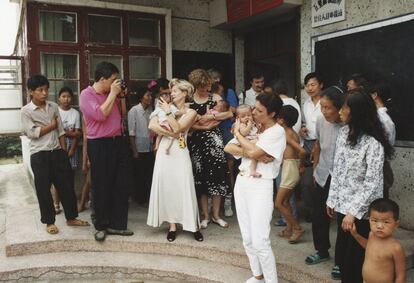 Seis familias belgas junto a los niños adoptados posan en la puerta del Centro Social de Acogida de Yueyang mientras los trabajadores y otros curiosos de la zona observan la escena, 1994.