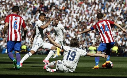 Los jugadores del Atlético de Madrid, Koke Resurrección (i) y Gabi Fernández (d), y los del Real Madrid, Caseimiro (2i) y Luka Modric (suelo).