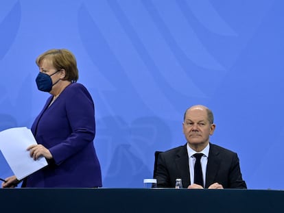 La canciller en funciones, Angela Merkel, llega a la rueda de prensa para anunciar las nuevas restricciones y se sienta junto a su sucesor, Olaf Scholz, este jueves en Berlín.