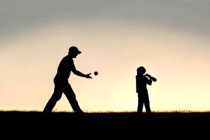 Un padre juega con su hijo al beisbol.