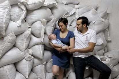 José Luis Monrós con su hermana Celia y el bebé de esta junto a sacos de chufa, materia prima de la Horchatería Alboraya.