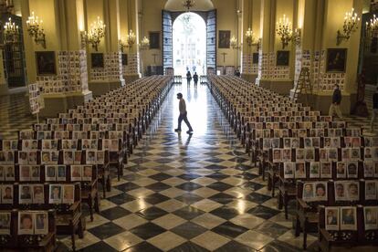 Un hombre camina entre los retratos de personas fallecidas por el coronavirus, dentro de la catedral de Lima (Perú).