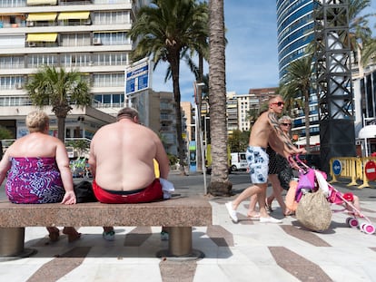 Dos turistas sentados en un banco del paseo marítimo de Benidorm, Alicante.