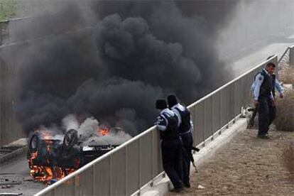 Policías iraquíes observan un coche en llamas tras la explosión de una bomba en Bagdad.
