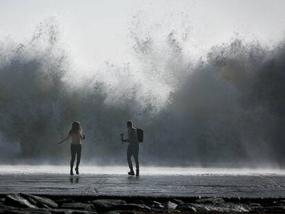 Una parella intenta fer una foto a la platja de Barcelona.