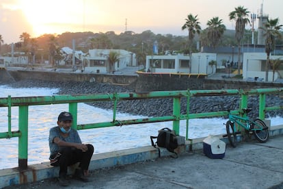 Un viejo pescador descansa con un cigarro en la mano mientras cae el sol sobre el viejo muelle de La Libertad. De fondo se aprecian las nuevas obras del malecón, a ser inauguradas en breve.