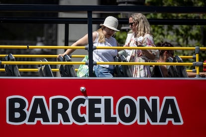 En la imagen, dos turistas sobre un bus turístico este viernes en plaza Catalunya. [ALBERT GARCIA] EL PAIS
