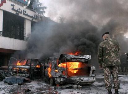 Un militar observa varios coches ardiendo tras el atentado.