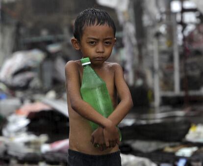 Un niño lleva una botella de agua bajo la lluvia en la ciudad de Tacloban.