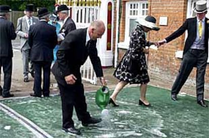 Varios asistentes a las carreras de Ascot, desinfectándose los zapatos.