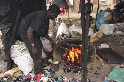 Henry Karisa quema prendas usadas para freír cacahuetes en el mercado de ropa de segunda mano de Kongowea, en la ciudad keniana de Mombasa.