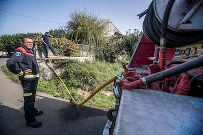 Miembros de protección civil abastecen a una vivienda de Carballo (A Coruña) con un camión cisterna.