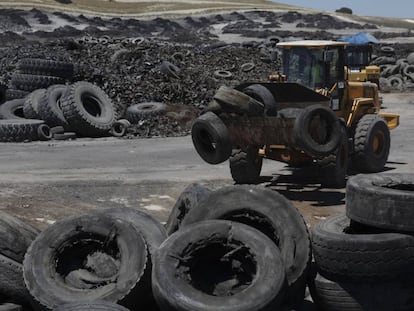 Una excavadora transporta los neum&aacute;ticos que no ardieron en Sese&ntilde;a.