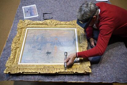 El restaurador Christian Chatellier inspecciona el cuadro 'Impresión, Sol naciente' del pintor Claude Monet, antes de colocarlo en la exposición 'Hodler Monet Munch. Peindre l'impossible' en el Museo de la Fundación Pierre Gianadda, en Martigny (Suiza).