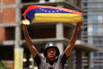 Una persona sostiene una bandera venezolana durante la protesta convocada por la opositora María Corina Machado, en Caracas, (Venezuela). 