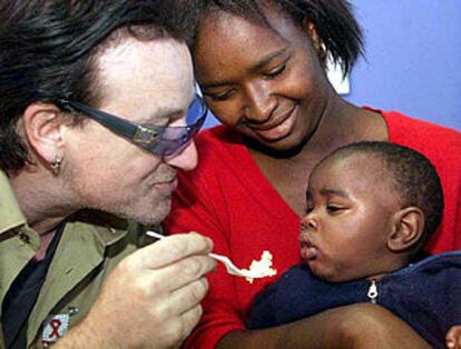 Bono da de comer a Thomas Qubile, de 11 meses, enfermo de sida, ante su madre, Mpumelelo, ayer en Soweto.