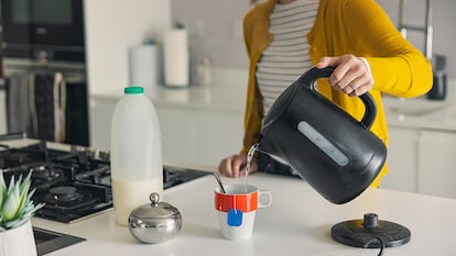 Una mujer echándole agua desde el hervidor a su taza de té.