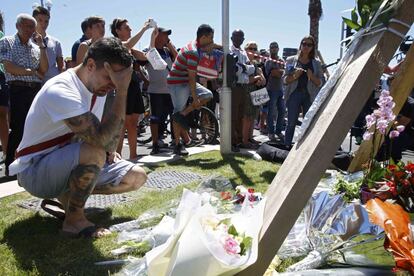 Un hombre arrodillado frente a los ramos de flores que se han ido depositando como homenaje cerca de la escena del atentado en Niza, Francia. 