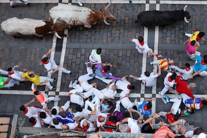 Un grupo de mozos caen al suelo al paso de los toros de la ganadería Victoriano del Río Cortés durante el cuarto encierro de los Sanfermines, este jueves.