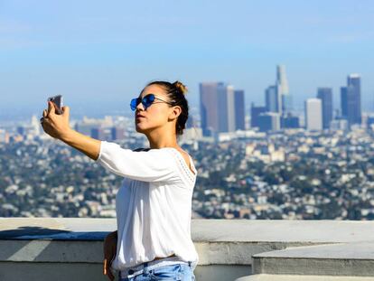 Una mujer joven se toma un "selfie" desde el observatorio Griffith con la ciudad de Los Ángeles detrás, en California (Estados Unidos)