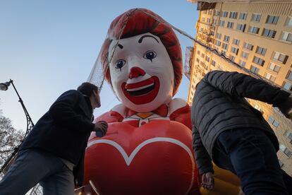 Personas caminan por debajo del globo de Ronald McDonald, el payaso que representa a la franquicia de comida rápida. 