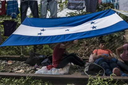 Una pareja hondureña se protege del sol con la bandera de su país.
