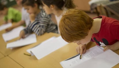 Unos ni&ntilde;os leen un texto en un colegio