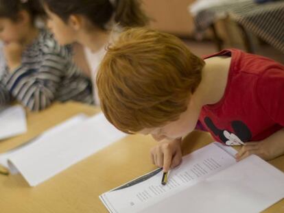 Unos ni&ntilde;os leen un texto en un colegio