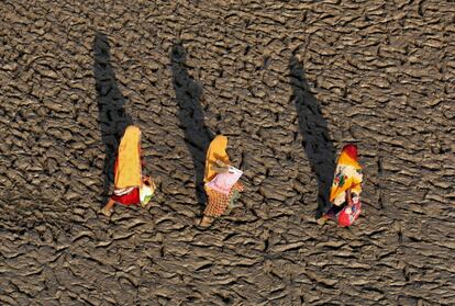 Mujeres caminan en las orillas fangosas del río Ganges después de darse un baño sagrado, en Allahabad (India).