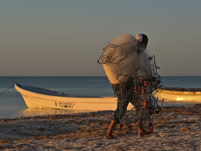 Un pescador carga sus redes mientras se prepara para salir a pescar desde un puerto en Yucatán (México).