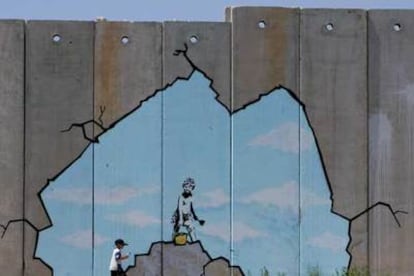 Un niño palestino pasa junto a una de las pinturas del muro de Gaza.