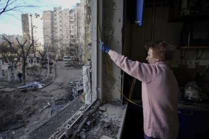 Una mujer mide una ventana rota antes de cubrirla con láminas de plástico en un edificio en Kiev. El Kremlin rehusó este martes comentar una información publicada y eliminada enseguida en un tabloide ruso, que hablaba de casi 10.000 soldados de las tropas de Putin muertos durante la campaña en Ucrania.