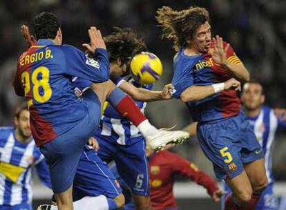 Sergio Busquets y Puyol intentan despejar ante Román.