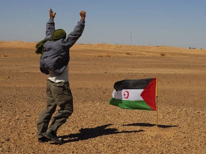 Un miembro del Frente Polisario se manifiesta ante los soldados marroqu&iacute;es, al fondo de la imagen,  apostados en el muro constru&iacute;do por Marruecos.