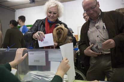 Un dona vota, acompanyada del seu gos, a un collegi de Barcelona.