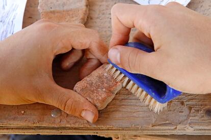 Un arqueólogo limpia un trozo de cerámica encontrado en el yacimiento.