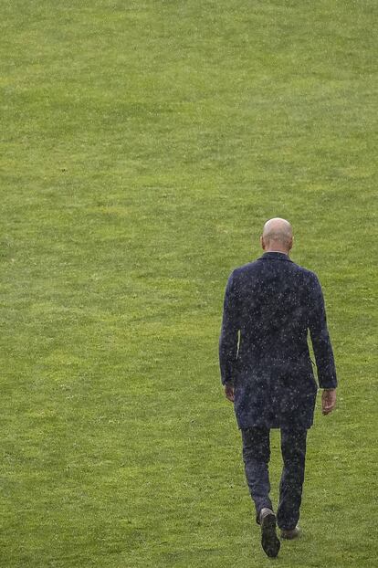Zinedine Zidane, bajo la lluvia, se dirige al banquillo del estadio de Vallecas.