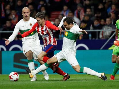 Luciano Vietto (c), intenta llevarse el bal&oacute;n ante los jugadores del Elche, Golobart (i) y Verd&uacute;.