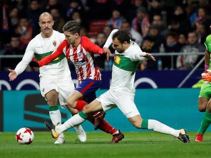 Luciano Vietto (c), intenta llevarse el bal&oacute;n ante los jugadores del Elche, Golobart (i) y Verd&uacute;.