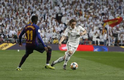 El centrocampista del Real Madrid, Luca Modric, corre con el balón ante Dembélé, del Barcelona.