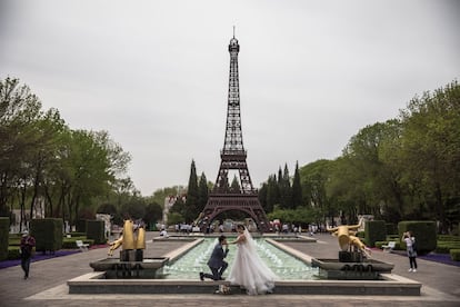 Una pareja posa frente a una réplica de la Torre Eiffel, en el World Park, para sus fotos de preboda, el 18 de abril de 2019, en Pekín (China).