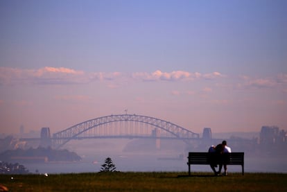 Una pareja observa el puerto de Sidney (Australia) cubierto de niebla.