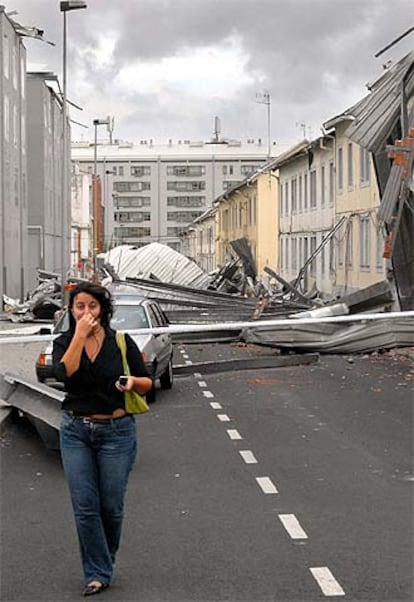 Una mujer camina por una calle de Caranza (Ferrol) llena de restos de tejados arrancados por el viento.