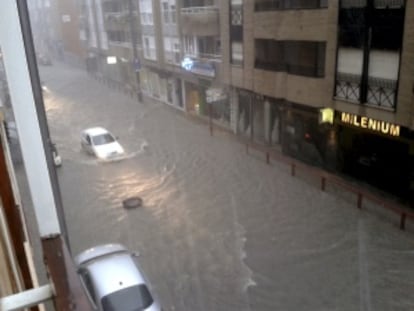 Un coche intenta atravesar una calle anegada hoy en la localidad murciana de Lorca.