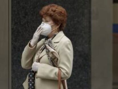 Una mujer camina con una mascarilla FFP2.