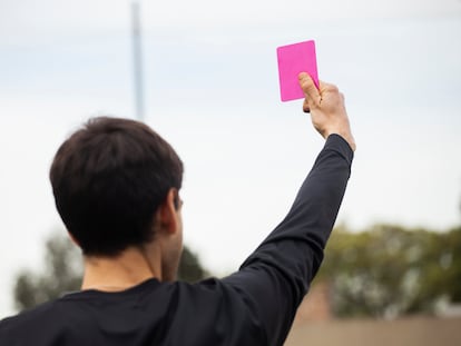 Un integrante del cuerpo técnico muestra una tarjeta rosa, en una fotografía ilustrativa.