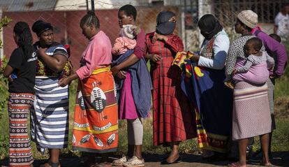 Una fila de mujeres, algunas con sus hijos a cuestas, esperan recibir comida en un barrio de Johannesburgo (Sudáfrica).