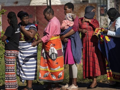 Una fila de mujeres, algunas con sus hijos a cuestas, esperan recibir comida en un barrio de Johannesburgo (Sudáfrica). 