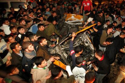 Los palestinos del campo de refugiados de Yabalia se agolpan en torno al coche atacado hoy por Israel.