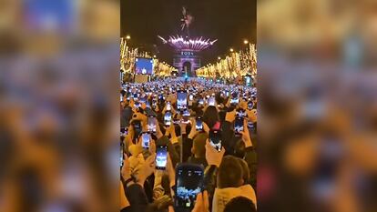 Miles de ciudadanos graban con sus móviles el espectáculo de Nochevieja en los Campos Elíseos de París.
